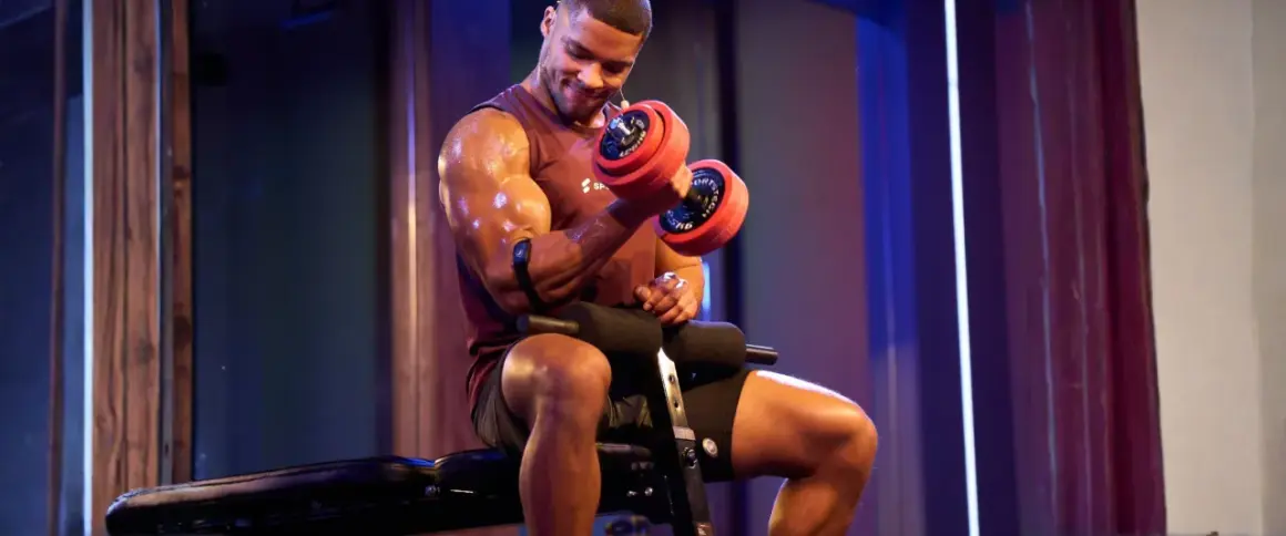 Mann mit Hantel beim Fitness-Training. Schweißglänzende Muskeln, konzentrierter Blick.