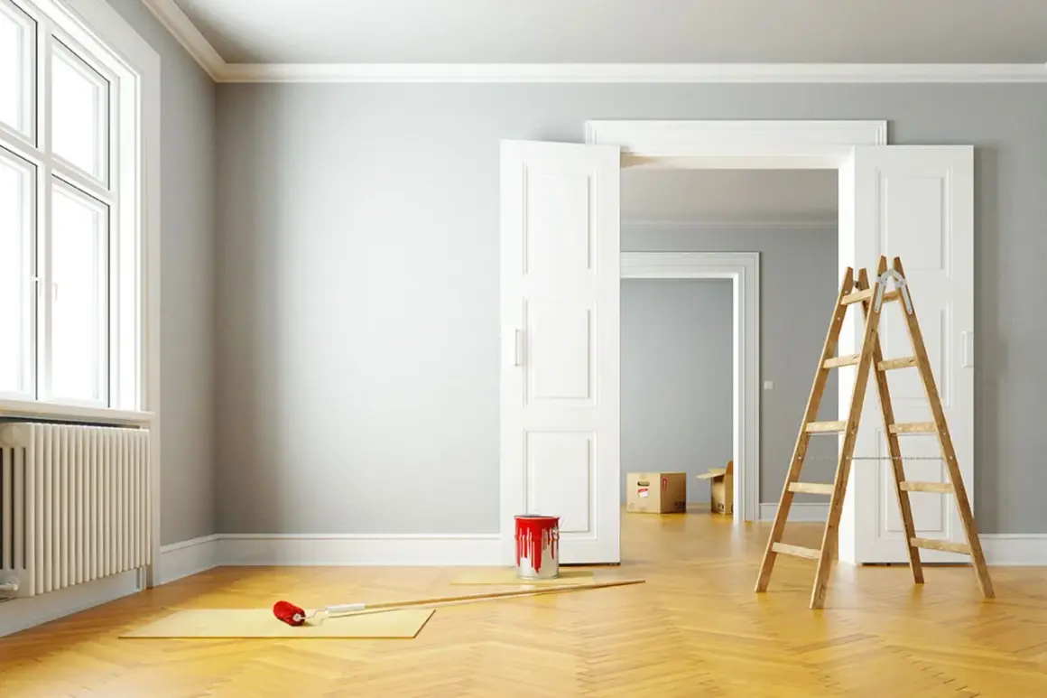 Leere Wohnung bereit zur Renovierung. Ein Farbeimer und eine Leiter stehen bereit, um die Wände zu streichen.
