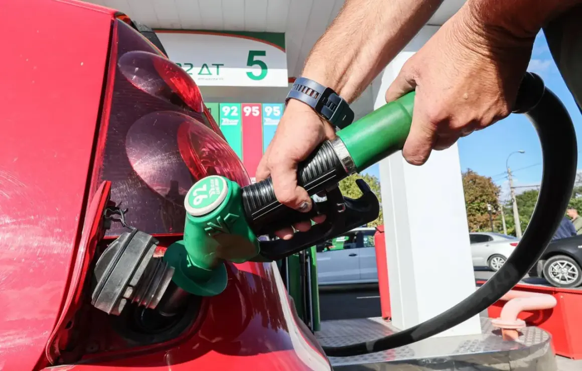 Remplissage d'une voiture thermique rouge à la station-service. Le pistolet vert est inséré dans le réservoir.