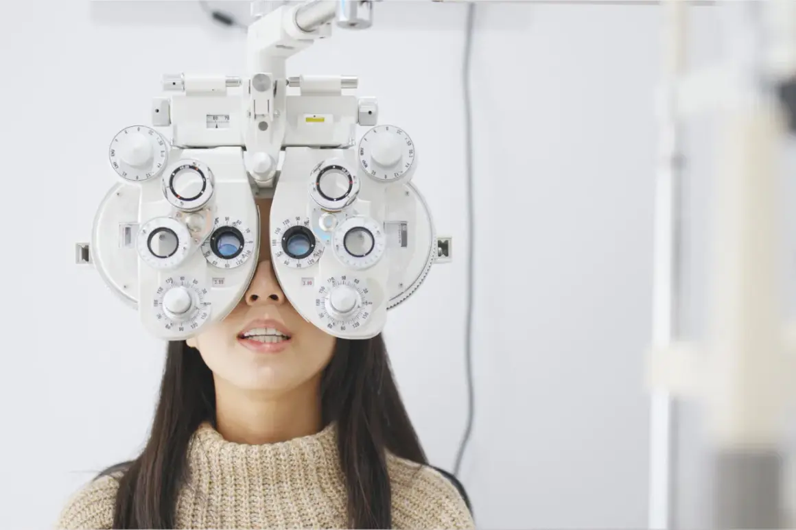 Kobieta z foropterem na twarzy, badana przez optometrystę. Ortoptysta ocenia jej wzrok.