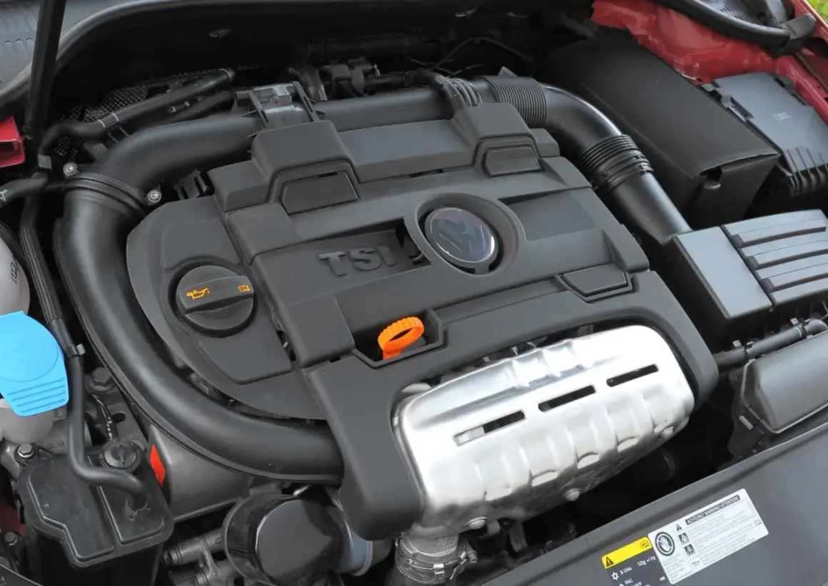Silnik 1.4 TSI z widocznym logo VW. Widoczne elementy układu dolotowego i osłony silnika.