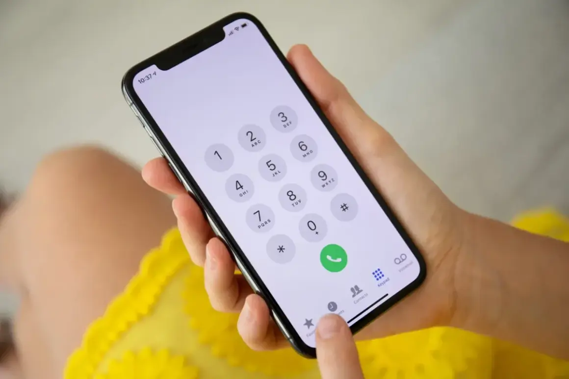 Dłoń trzyma smartfon z klawiaturą numeryczną. Możliwość wykonywania połączeń przez Wi-Fi ułatwia kontakt.