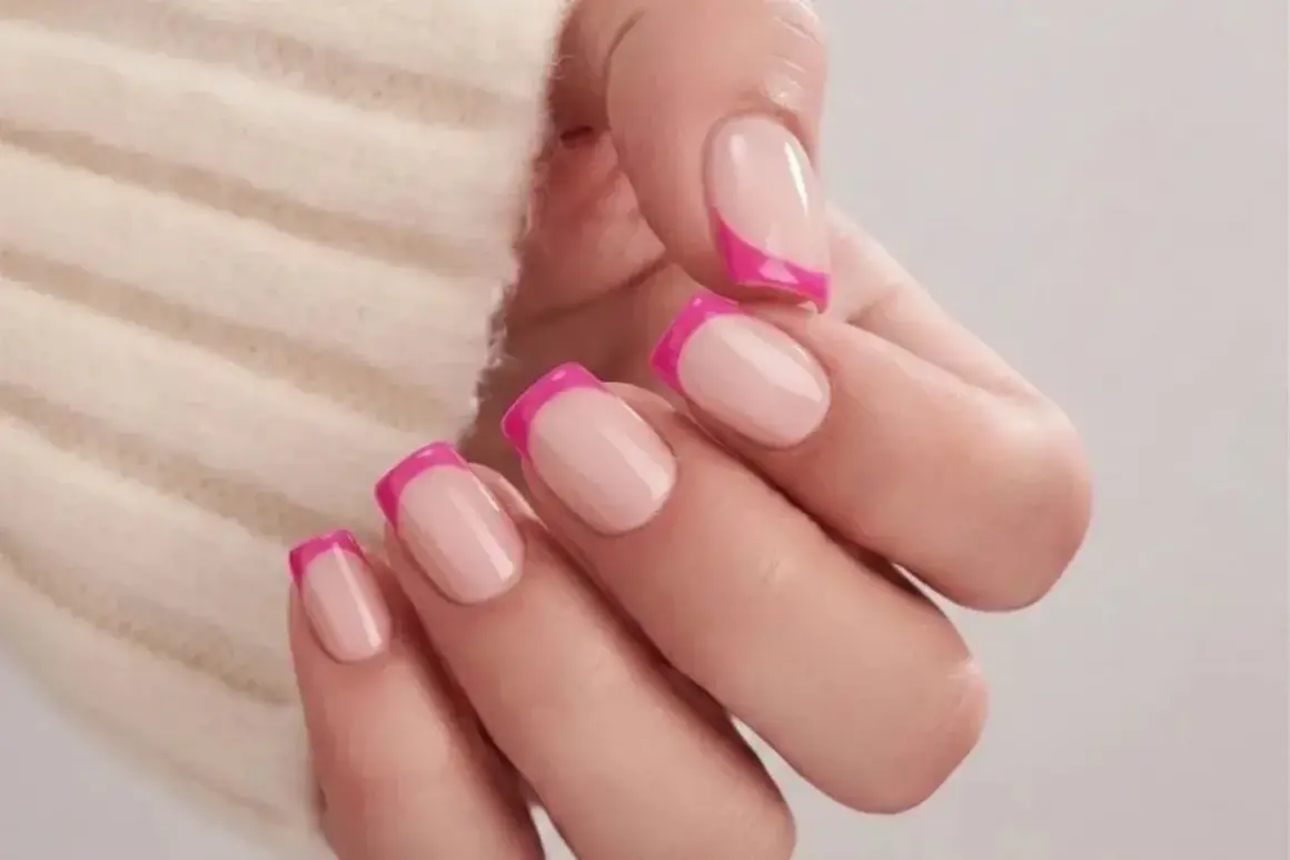 En hand med naglar i fransk manikyr med en modern twist av knallrosa. Olika nail types som visar en lekfull stil.