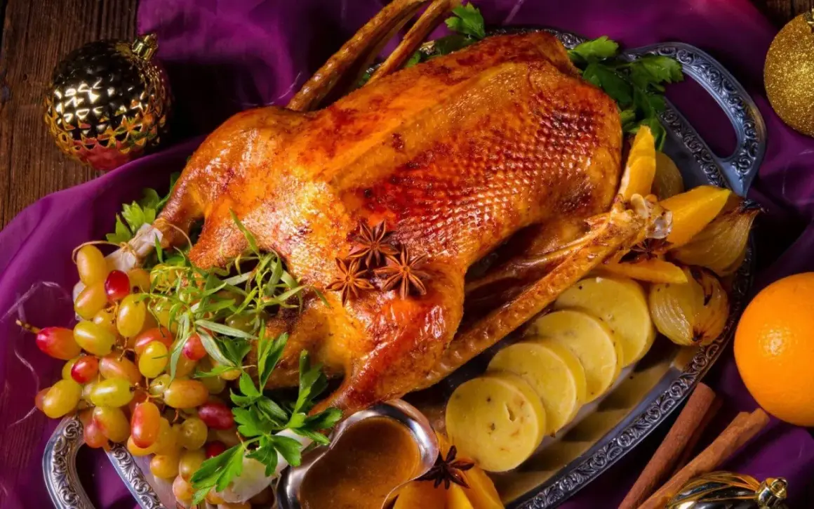 Eine goldbraune Gans auf dem Grill, garniert mit Trauben, Orangen und Sternanis. Perfekt für ein festliches Mahl.