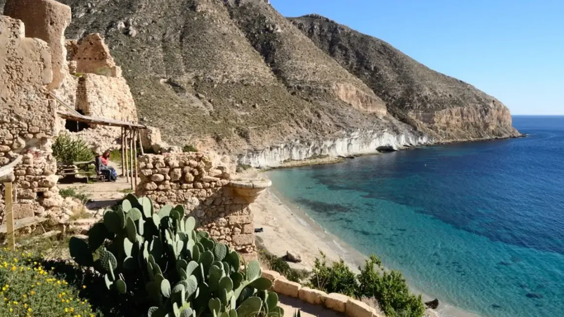 Ruinas de la hippie comuna Cala San Pedro, Almería, con mar turquesa y montañas.