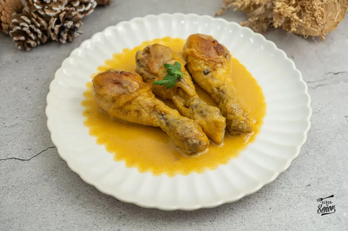 Tres jamoncitos de pollo dorados en una salsa cremosa, servidos en un plato blanco con un toque de perejil.