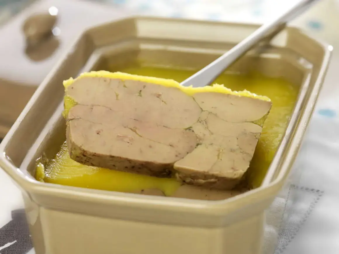 Tranche de foie gras au porto blanc, servie dans un plat en céramique avec une cuillère.