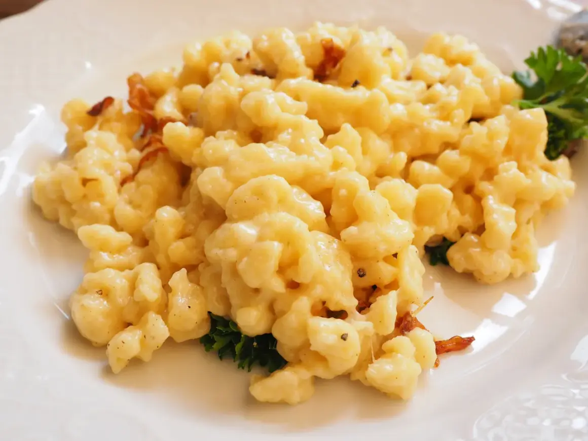 Gnocchetti di patate conditi con formaggio fuso e speck croccante, un classico dei primi piatti trentini.