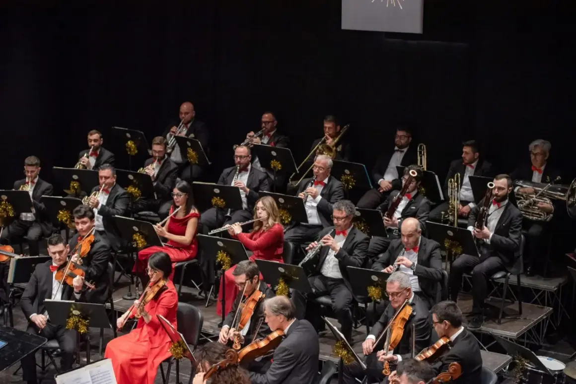 Orchestra di cantanti della Basilicata in concerto, con musicisti che suonano violini, flauti, ottoni e altri strumenti.