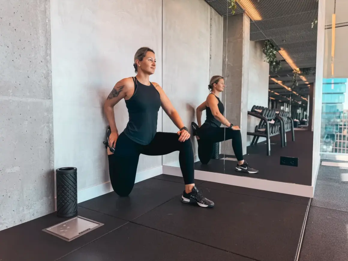 Frau dehnt sich im Fitnessstudio. Dies ist ein Beispiel dafür, was Gymnastik ist: Körperpflege und Bewegung.