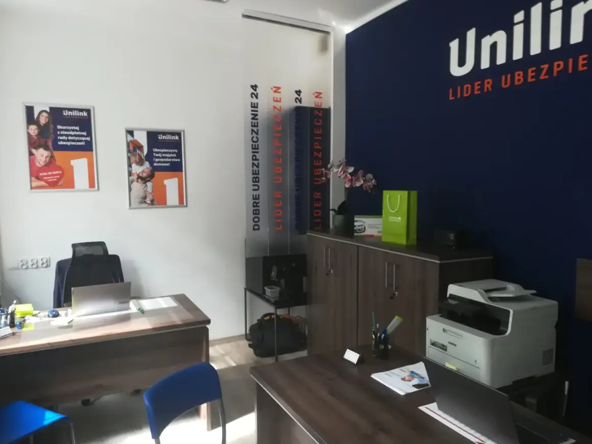 Biuro firmy ubezpieczeniowej Unilink z plakatami, drukarką i meblami.