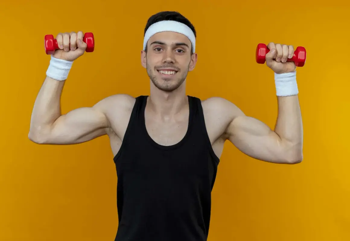 Ein Mann mit Stirnband und Schweißbändern macht Unterarmtraining mit roten Hanteln.