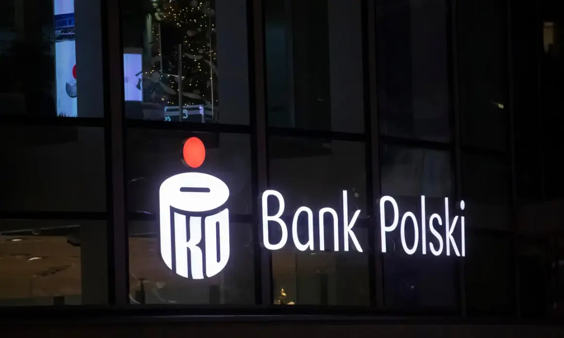 Świecący napis PKO Bank Polski. W tle choinka i odbicia. Inwestorzy liczą na dywidendę PKO BP.