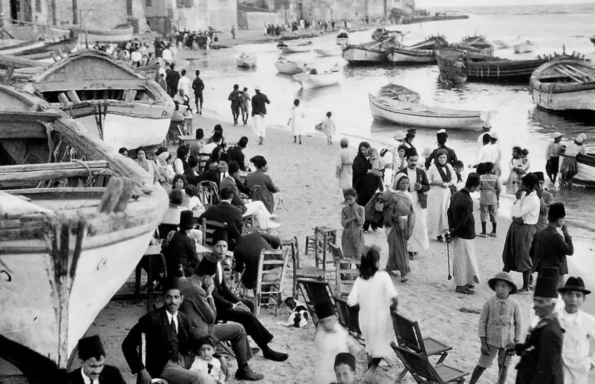 Gente en la playa con barcos, un vistazo al posible origen del conflicto entre Israel y Palestina.