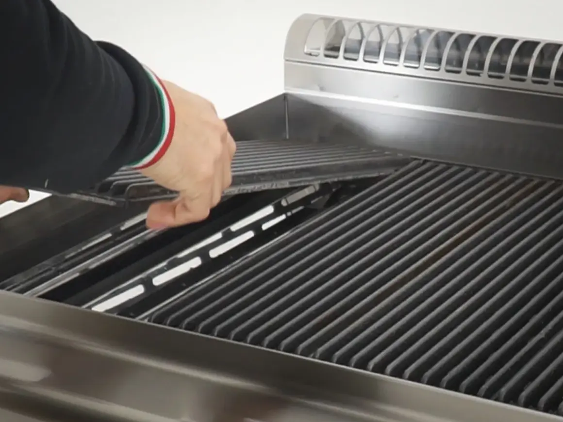 Mano che posiziona le pietre laviche nel barbecue a gas, pronte per una grigliata perfetta.