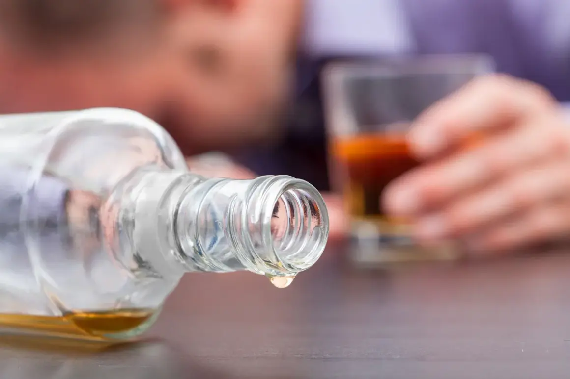 Ostatnia kropla alkoholu metylowego kapie z butelki. W tle niewyraźna postać trzyma szklankę z bursztynowym płynem.