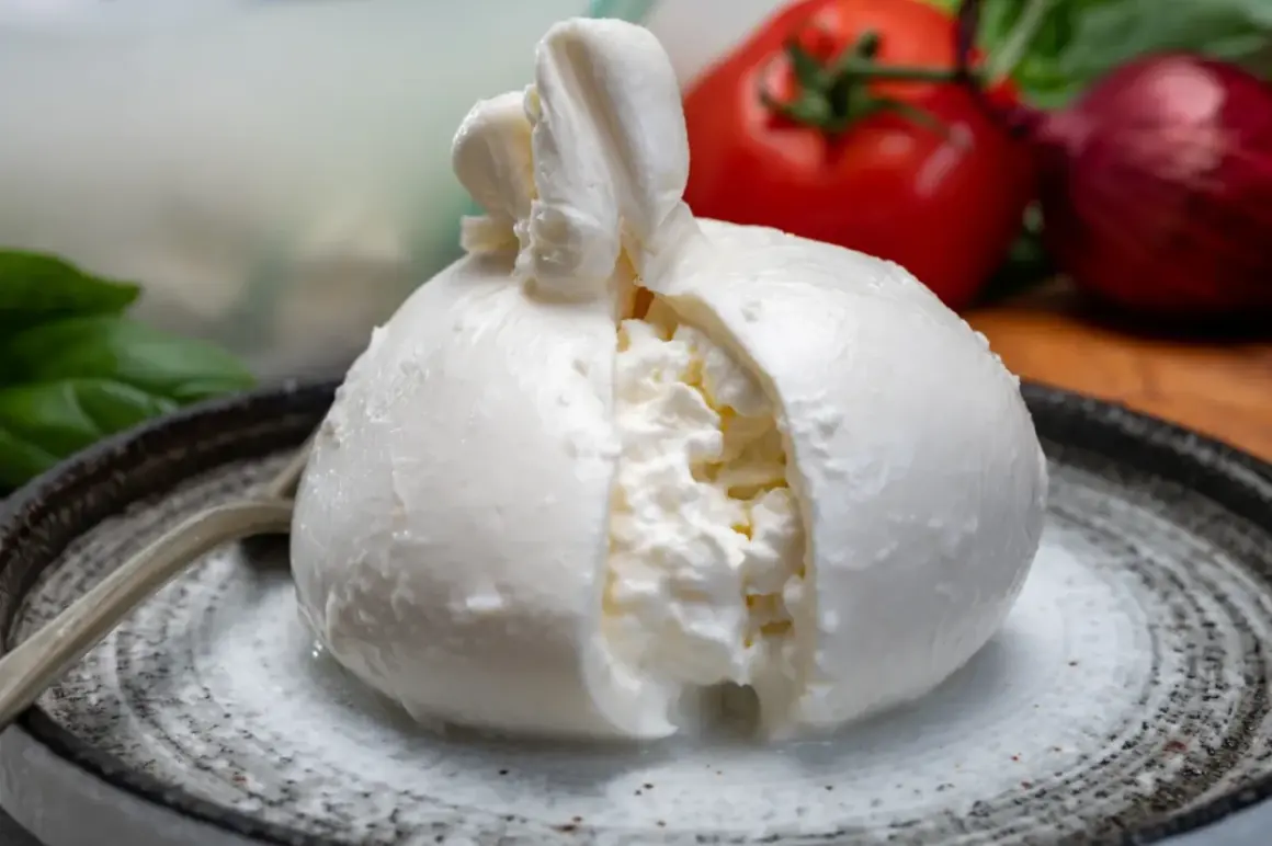 Pyszna burrata na talerzu, z pomidorem i cebulą w tle. Zastanawiasz się nad burrata kcal?
