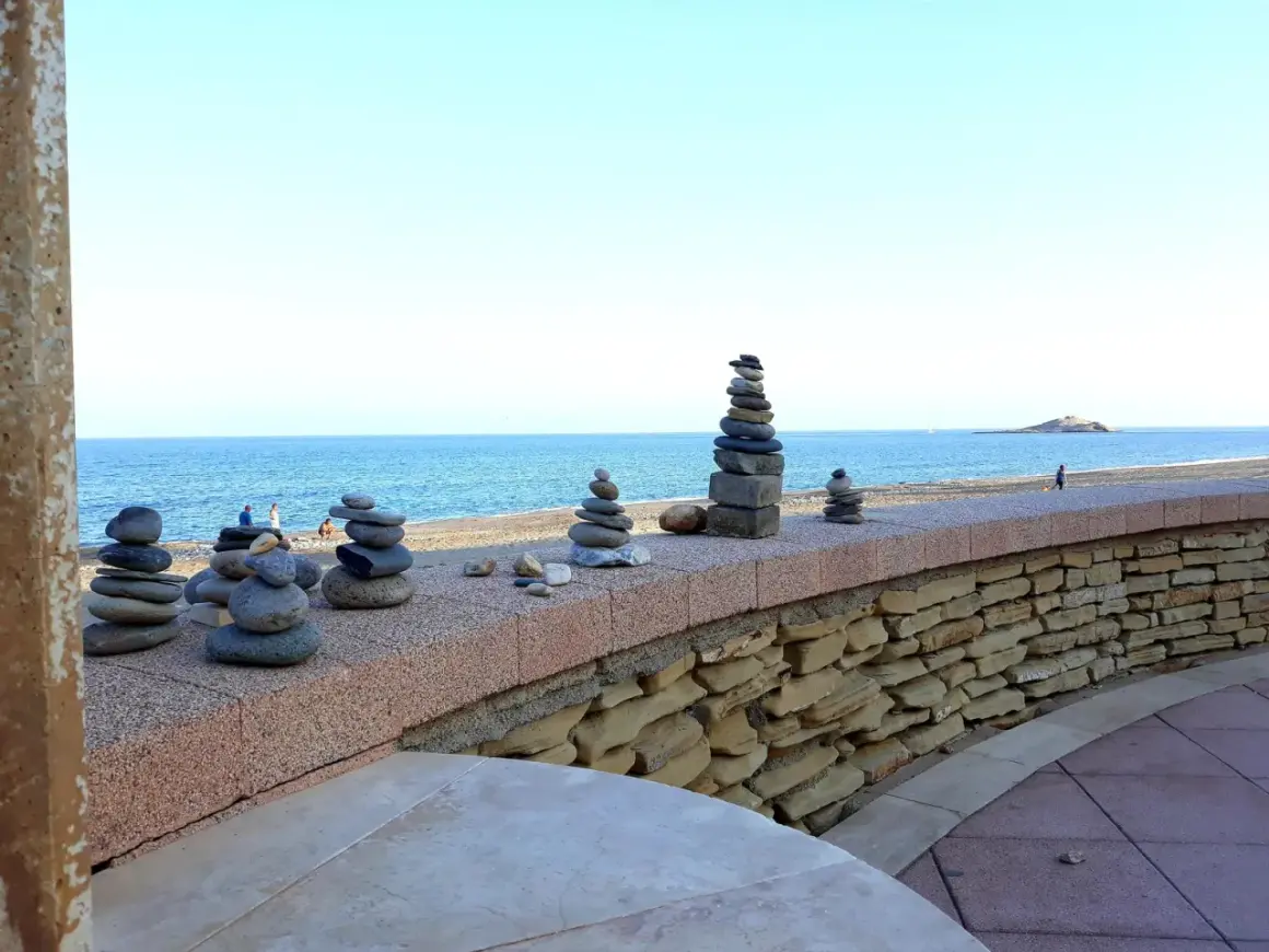 Torres de piedras en el **carboneras paseo marítimo**. El mar azul y el cielo despejado crean un fondo sereno para estas esculturas efímeras.