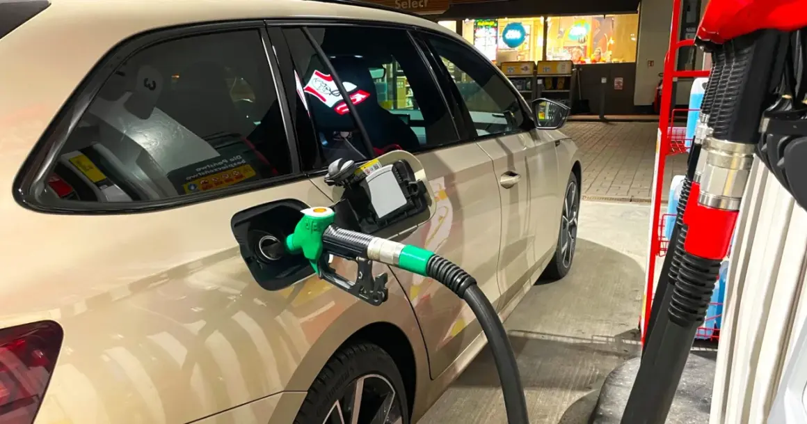 Tankowanie samochodu, zielony pistolet paliwa wlewa się do baku. Obawy o złej jakości paliwo diesel objawy mogą pojawić się po takiej wizycie na stacji.