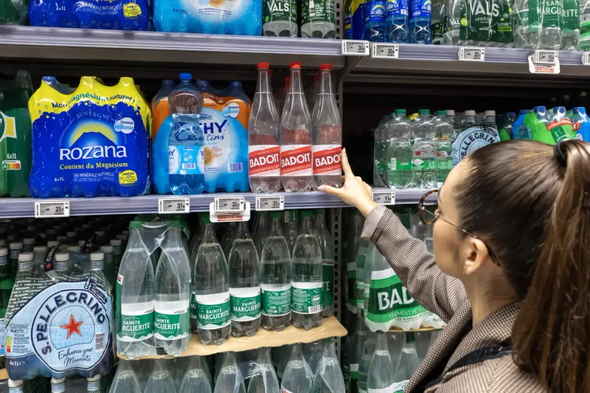 Une femme choisit une bouteille d'eau minérale Badoit. Les étiquettes indiquent la composition et le prix.