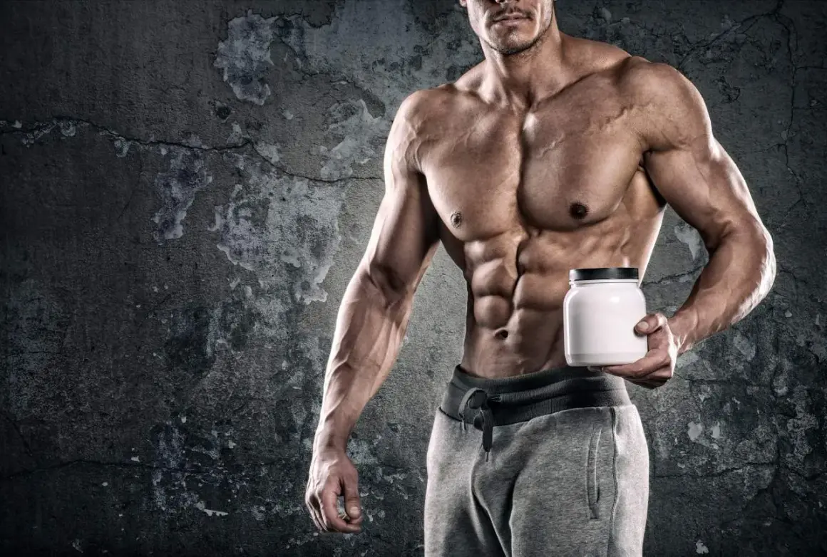 Muscoloso bodybuilder con addominali scolpiti tiene un barattolo bianco, simbolo di un efficace schema integrazione bodybuilding.