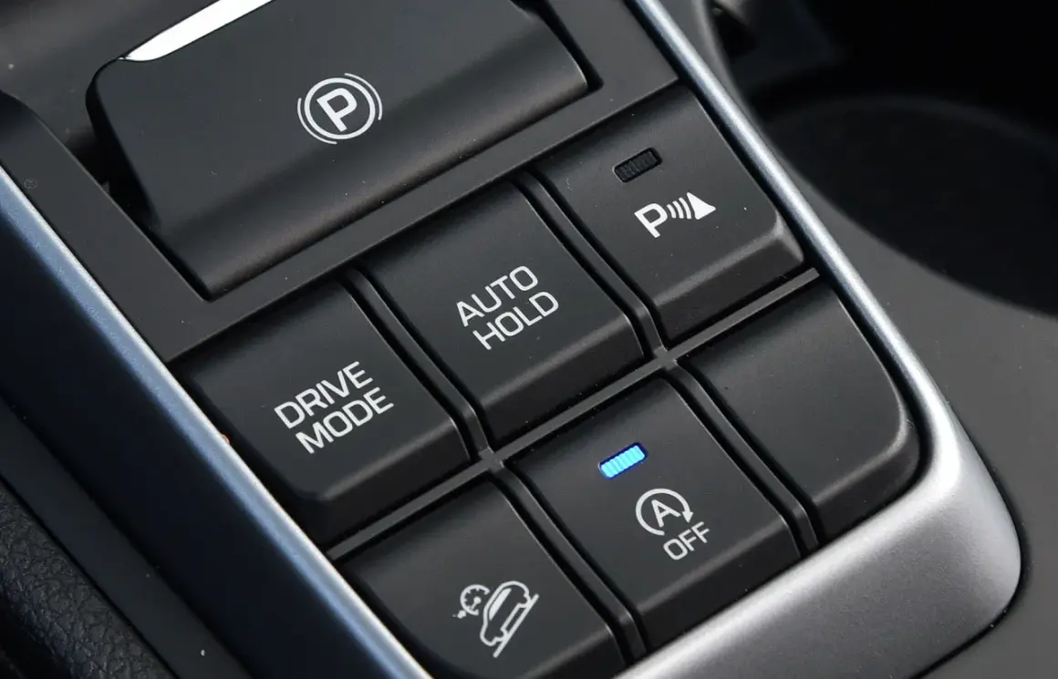 Przyciski w samochodzie: hamulec postojowy, Drive Mode, Auto Hold, asystent parkowania i system zapobiegający stoczeniu się na wzniesieniu (hill holder).