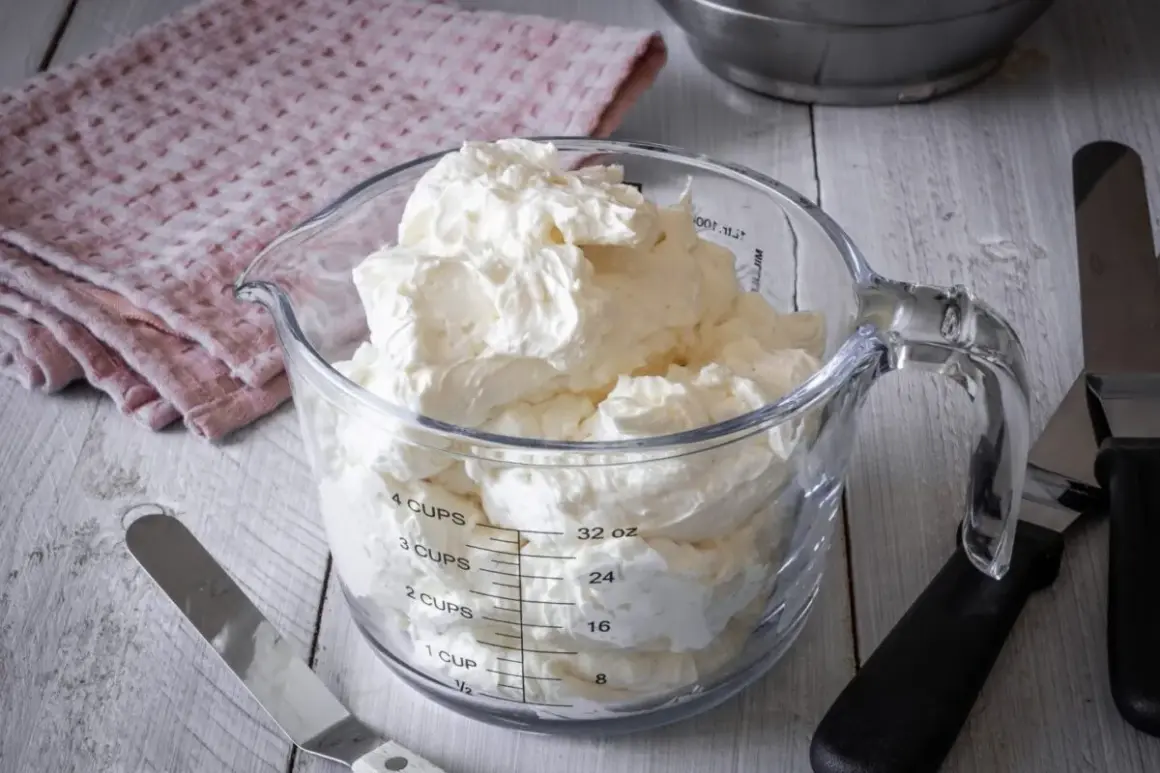 Ein Messbecher gefüllt mit luftiger Swiss Meringue Buttercreme, bereit für süße Kreationen.