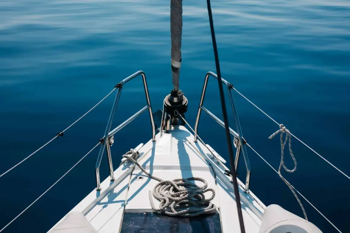 Prua di una barca a vela su un mare blu calmo. La prevalenza di una pompa è un concetto che non si applica a questa immagine.
