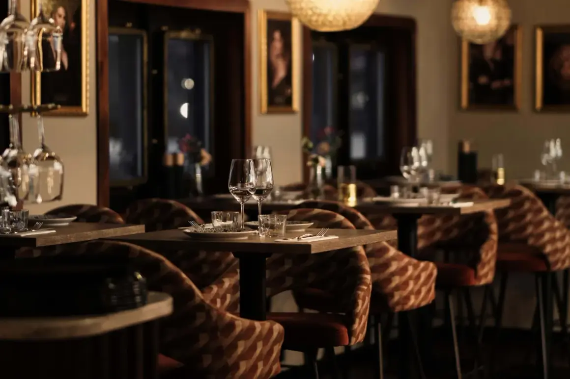 Mysig atmosfär på en av Stockholms nya restauranger. Dukade bord med glas och bestick, ombonade stolar och konst på väggarna.