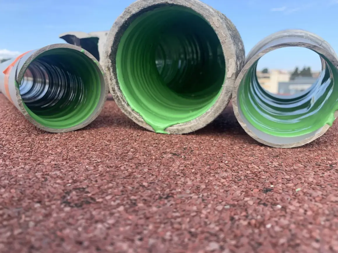 Trois tuyaux en PVC, dont un avec un revêtement vert vif, prêts pour enlever calcaire canalisation pvc.