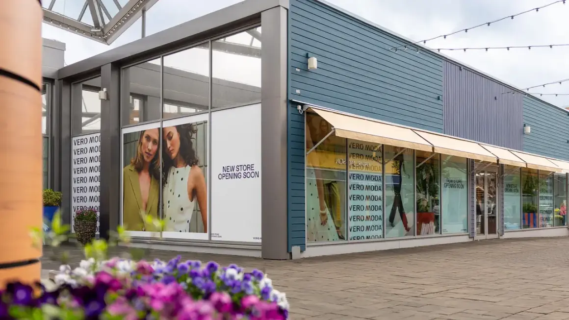 Vero Moda outlet med skyltar som visar "New Store Opening Soon". Blommor i förgrunden.