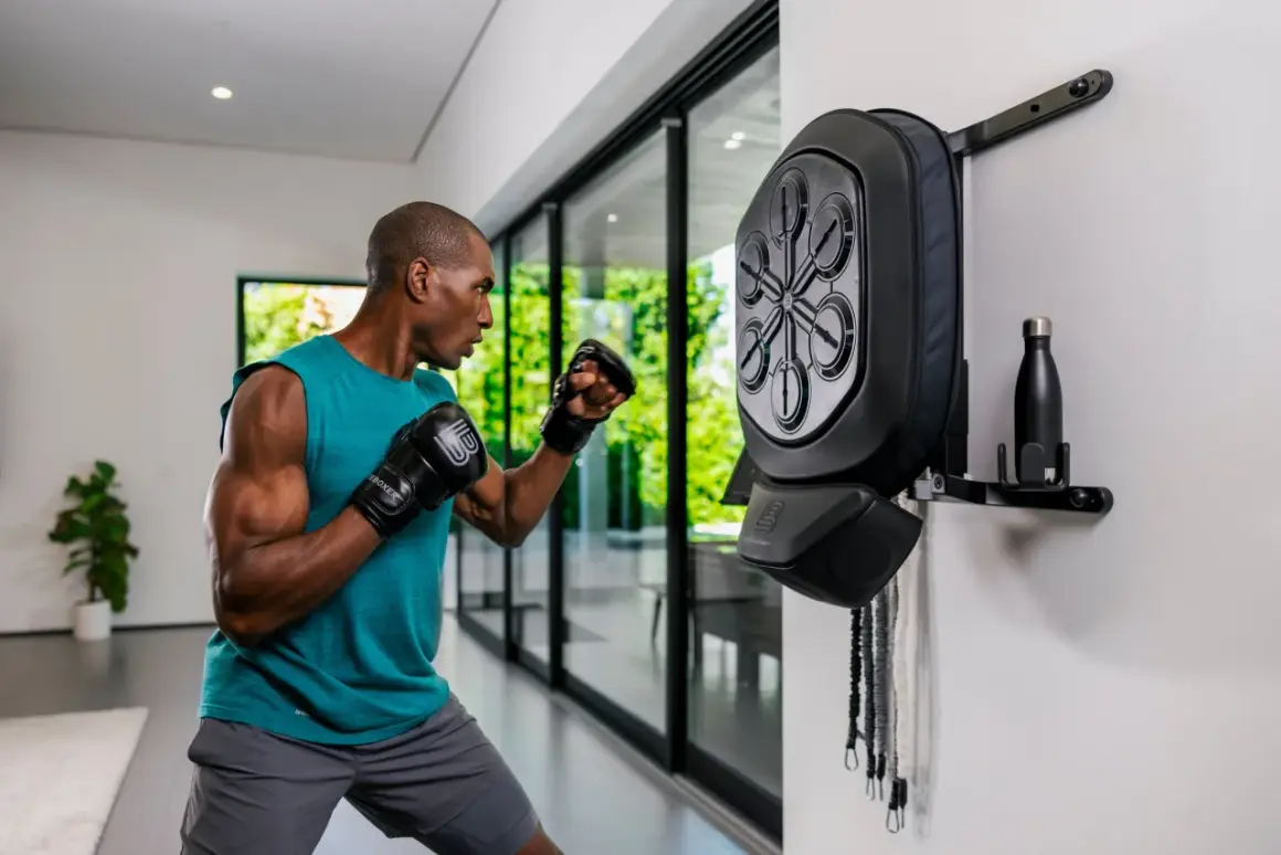 Man in a fighting stance throws a punch at a wall-mounted boxing reflex bag.