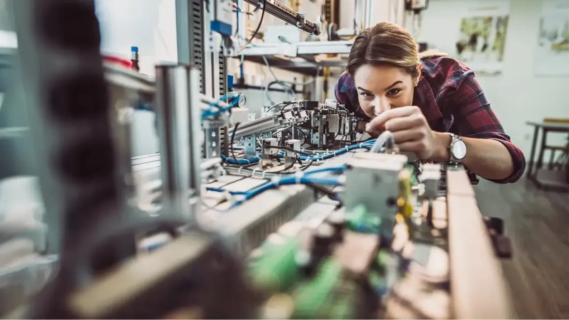 Junge Frau arbeitet konzentriert an einer komplexen Anlage im Bereich IU Elektrotechnik.