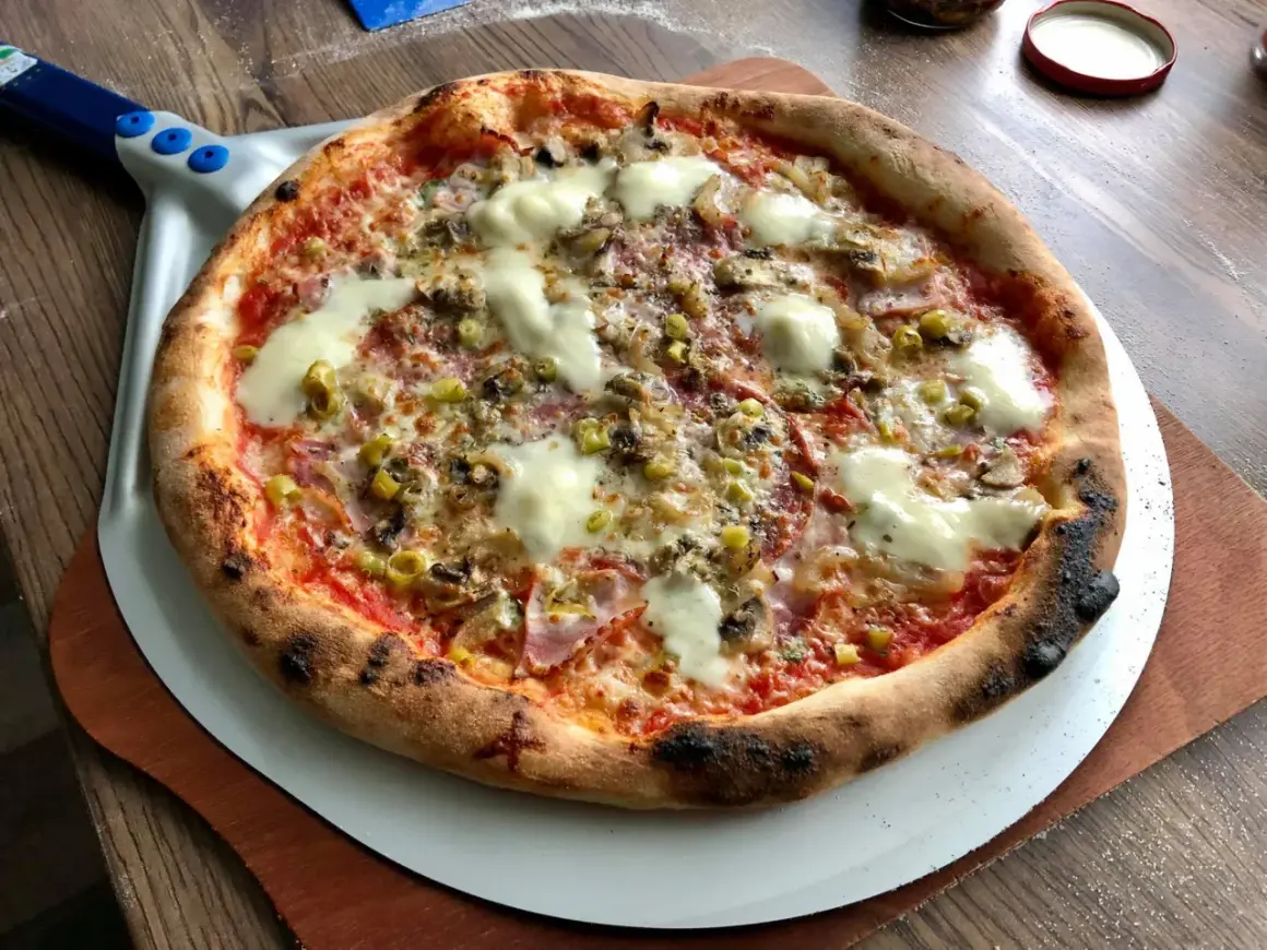 Gorąca, pachnąca prawdziwa pizza z ciągnącym się serem, pieczarkami i oliwkami, prosto z pieca na łopacie.
