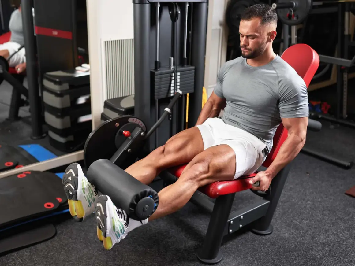 Mann trainiert den Beinstrecker Muskel an einem Gerät im Fitnessstudio.