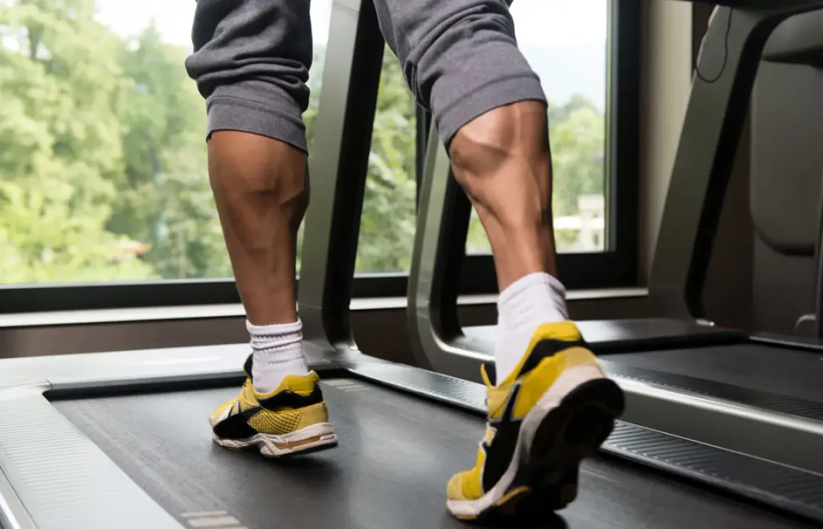 Jambes musclées sur un tapis roulant, mettant en valeur l'exercice mollet.