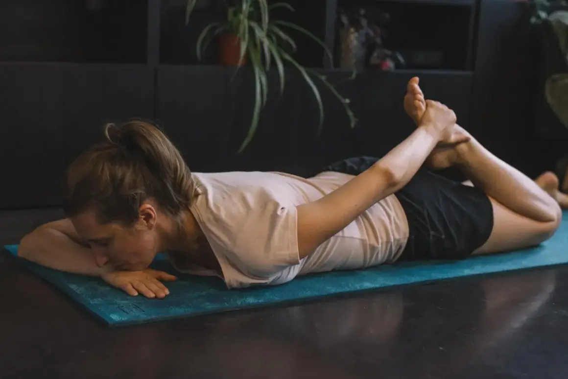 Femme pratiquant des exercices de yoga pour soulager la cruralgie, en position de cobra inversé sur un tapis bleu.