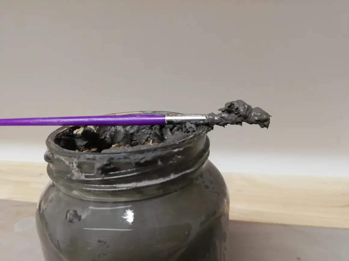 Pinceau violet trempé dans une pâte grise, prête à recoller terre cuite.