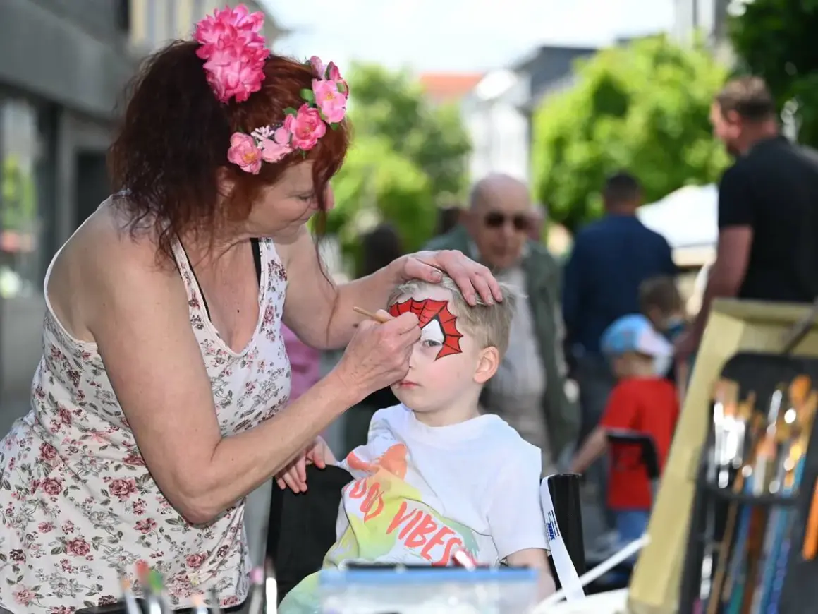 Kind wird beim Stadtfest in Radevormwald von einer Frau mit Spiderman-Maske bemalt.