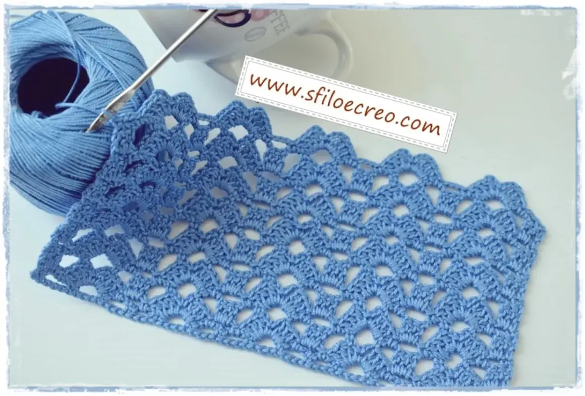 Uncinetto con filato azzurro crea un motivo a **punti traforati uncinetto** con un bordo ondulato.