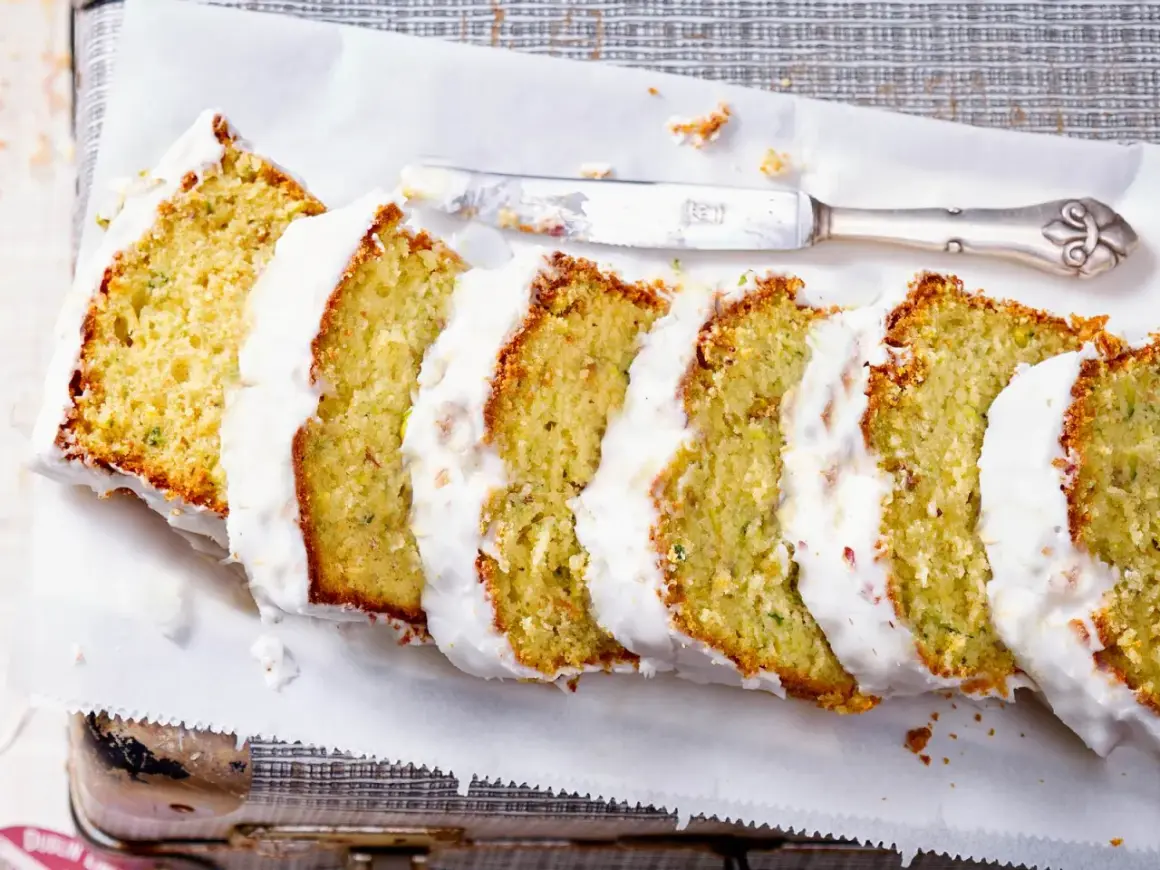 Saftiger Zucchini Kuchen mit weißer Glasur, in Scheiben geschnitten, bereit zum Genießen.