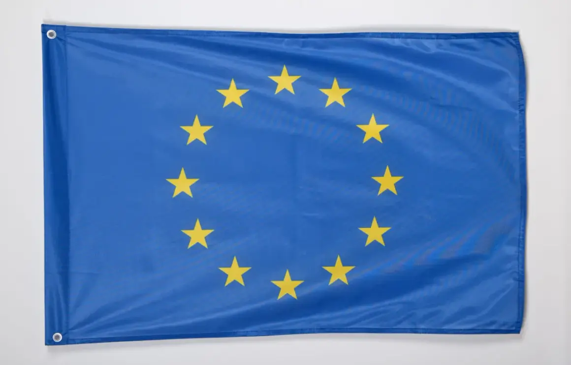 Flaga Unii Europejskiej z dwunastoma złotymi gwiazdami na niebieskim tle.