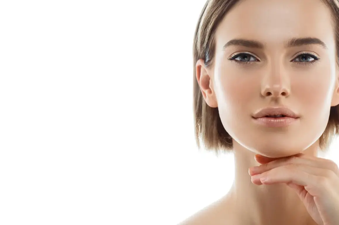 Primo piano di una donna con pelle luminosa e un tocco sul mento, un'ispirazione per chi cerca come snellire il viso con un look naturale.