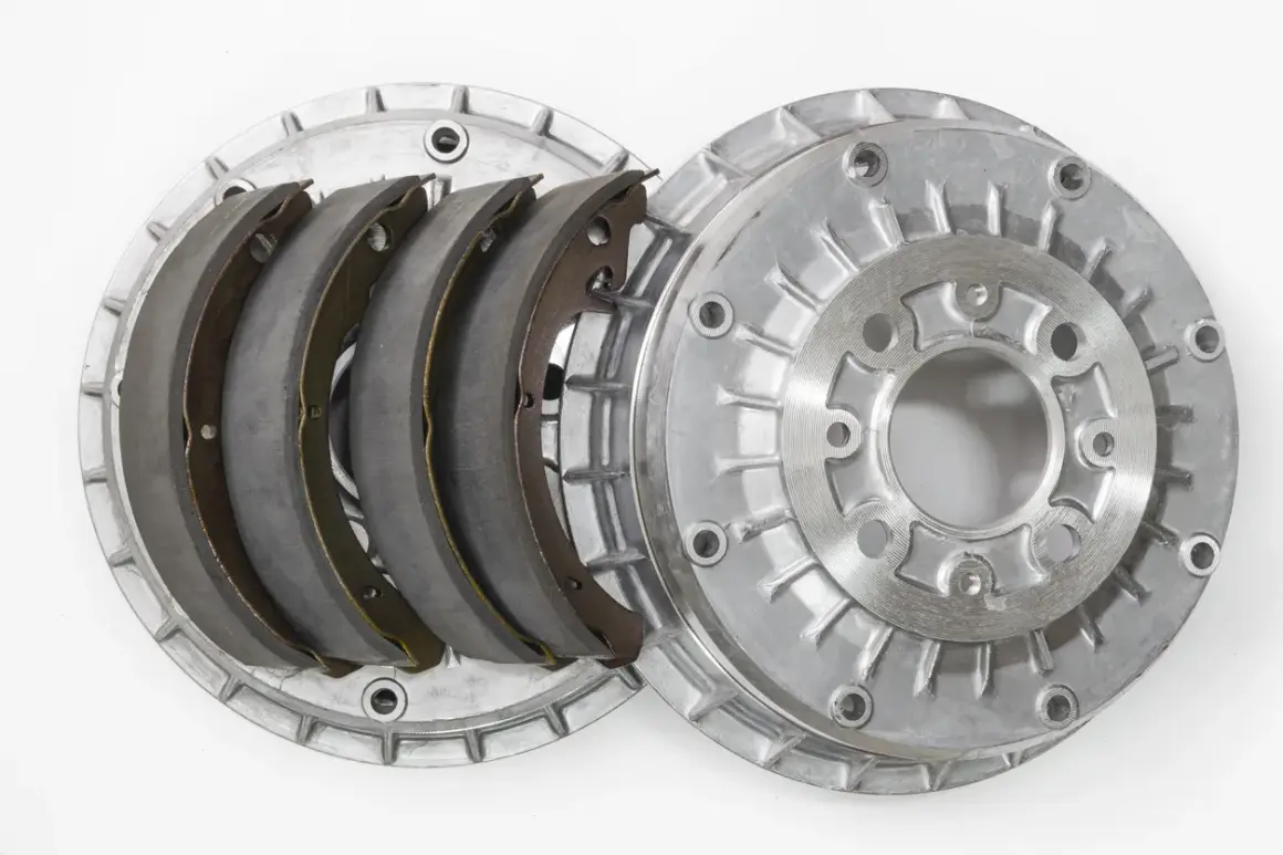 Pièces détachées d'un frein à tambour : mâchoires neuves et tambour en aluminium.