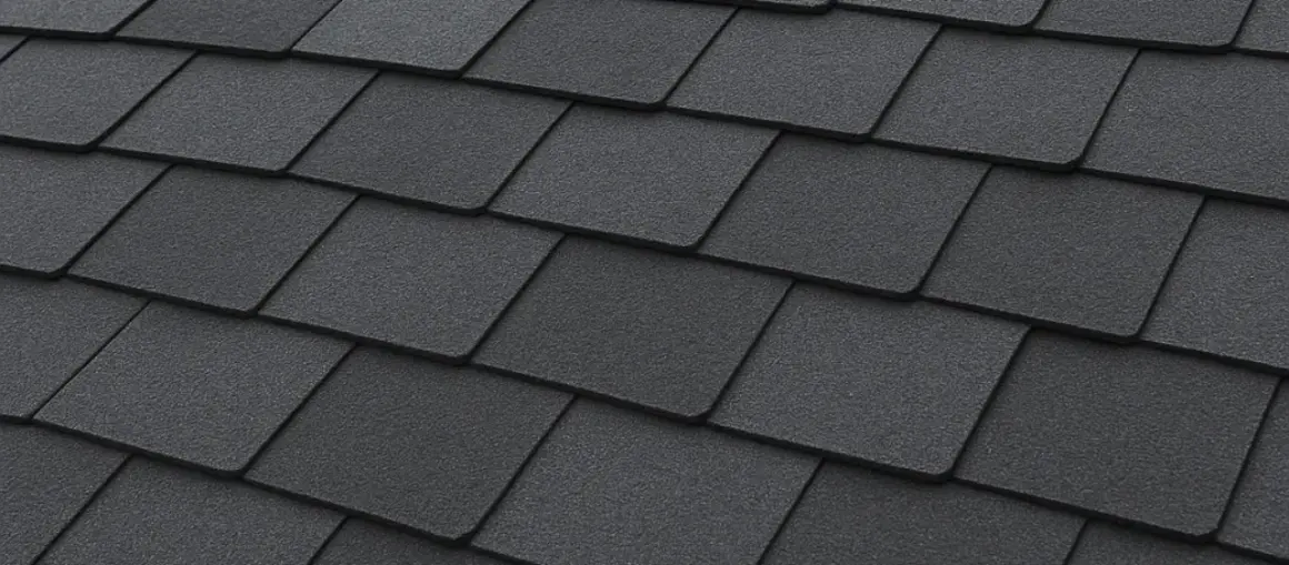 Close-up of dark grey, textured recycled shingles on a roof, showcasing their layered pattern and durable appearance.