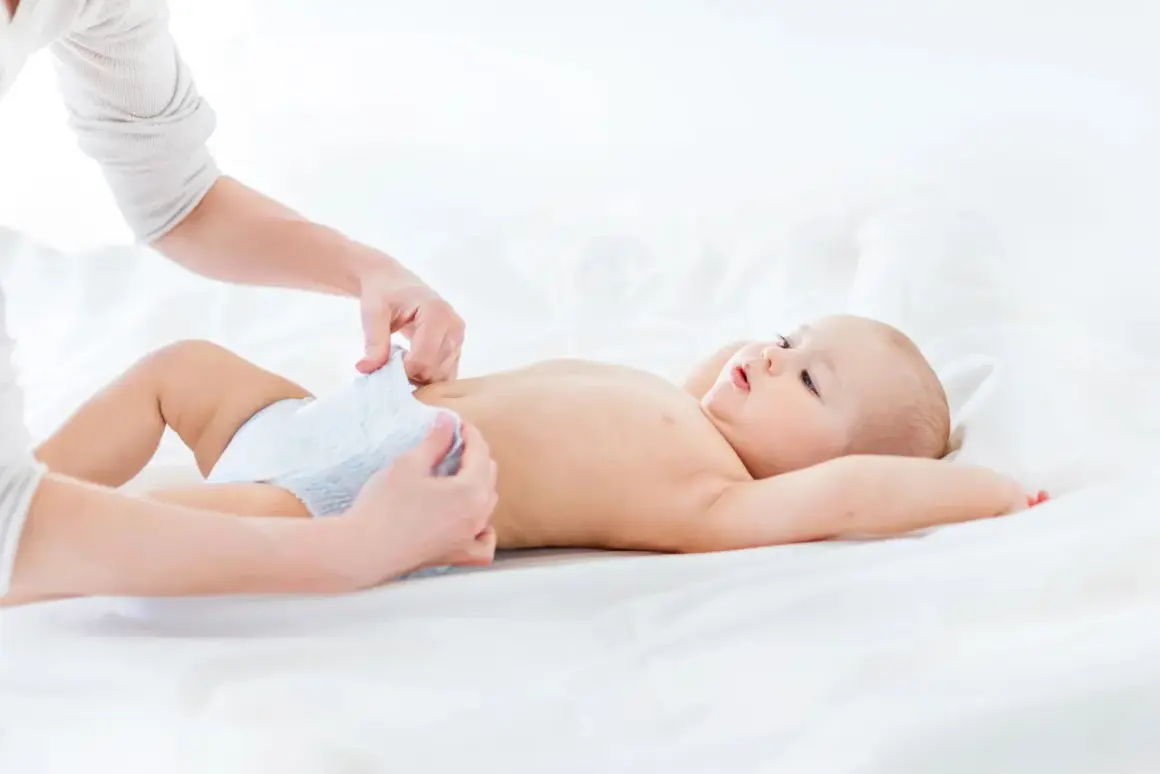 Mama zmienia pieluszkę, a maluch ma czarną kupę.
