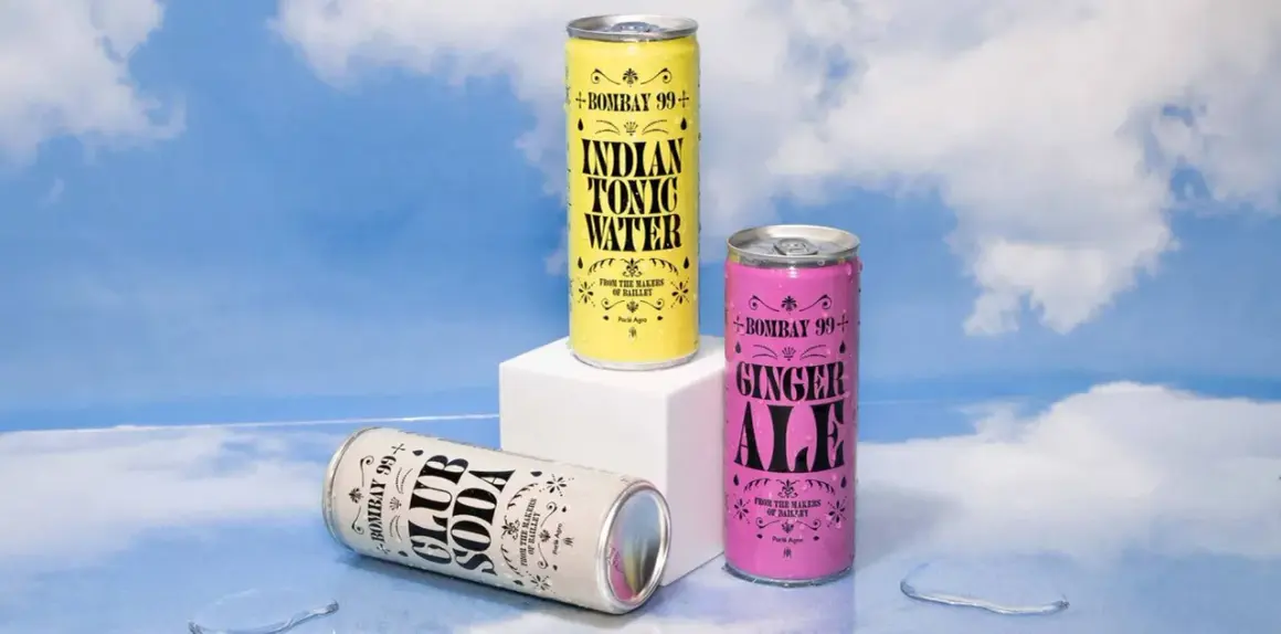 Three Bombay 99+ cans: Club Soda, Indian Tonic Water, and Ginger Ale, styled by Jessica Walsh, against a sky backdrop.