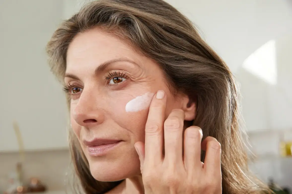 Frau trägt abends keine Creme ins Gesicht, sondern nur einen Tupfer auf die Wange.