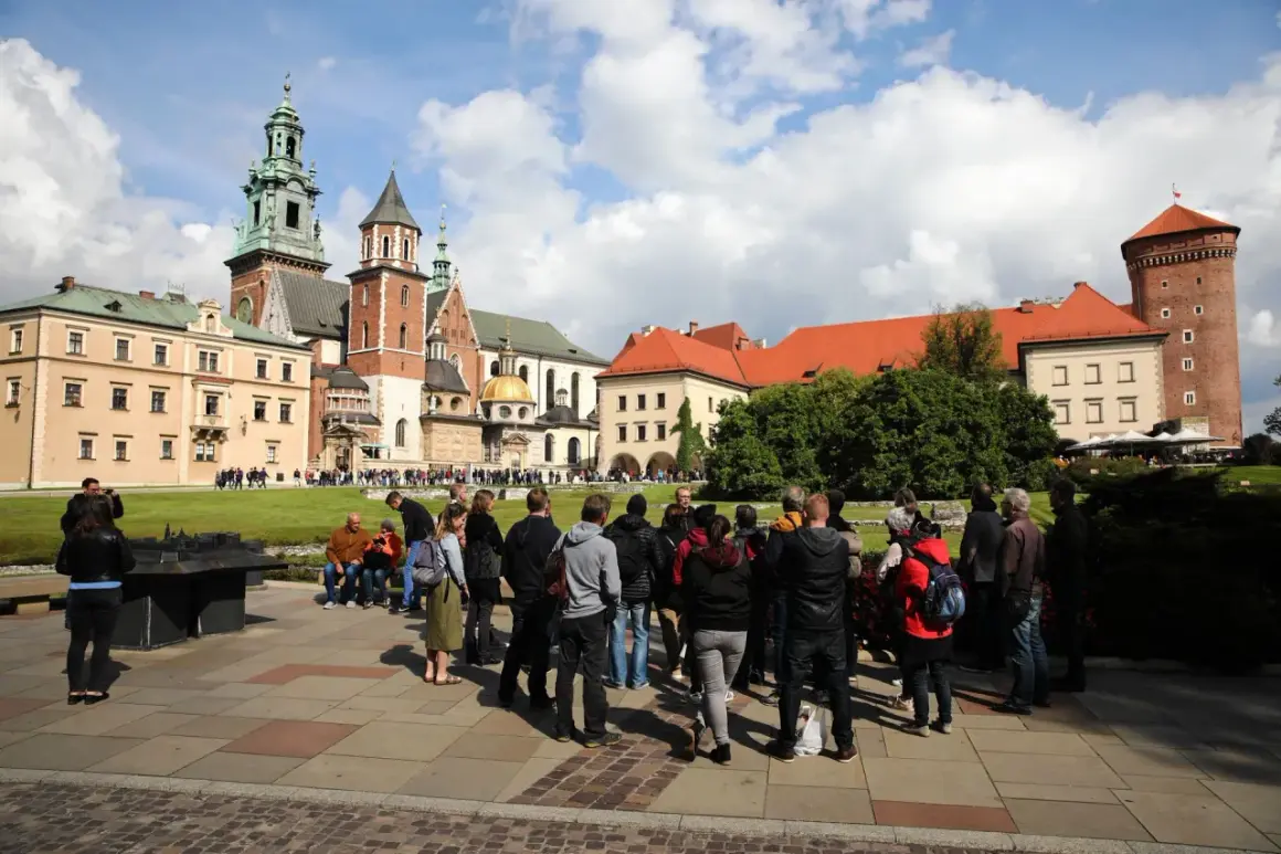 Grupa turystów zwiedza Wawel. Sprawdzają wawel bilety cennik przed wejściem.