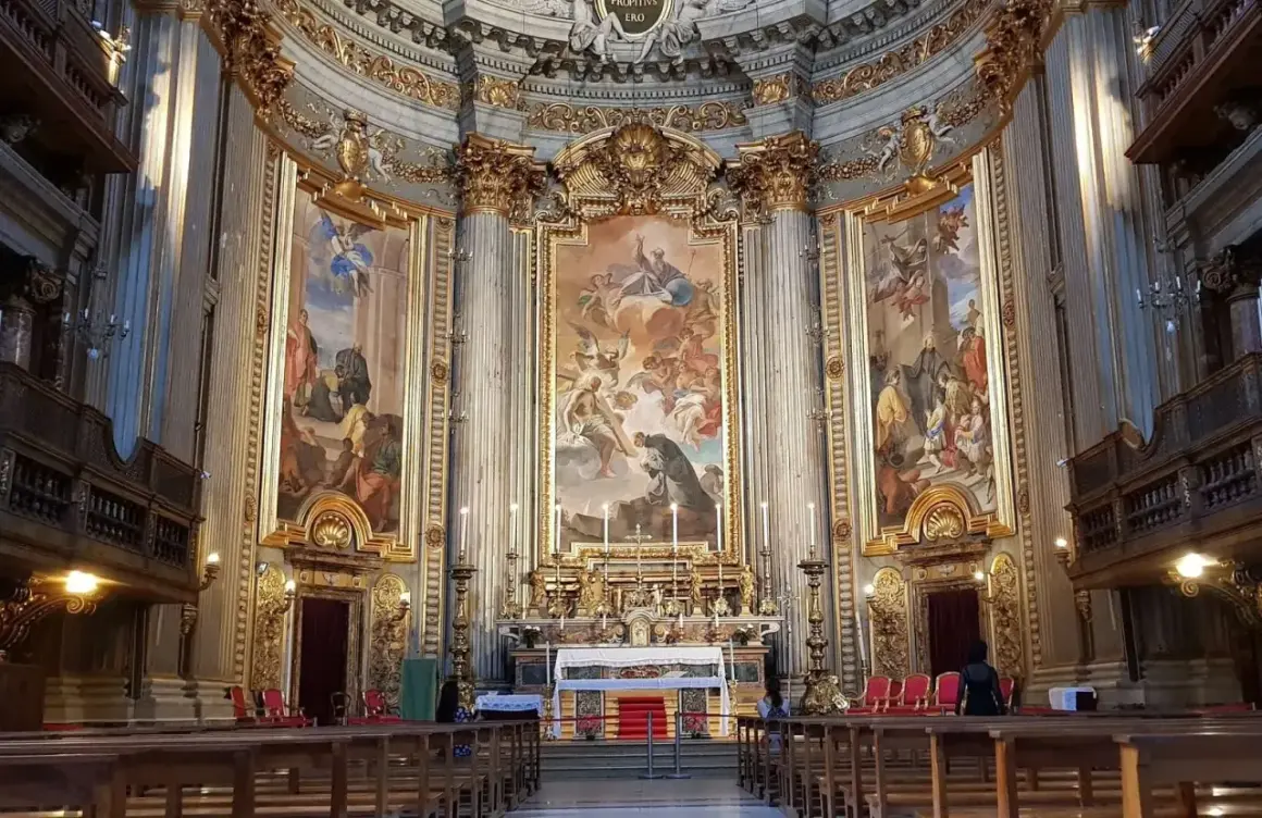 Interno della chiesa di Sant'Ignazio di Loyola, con affreschi barocchi, altare dorato e panche in legno.